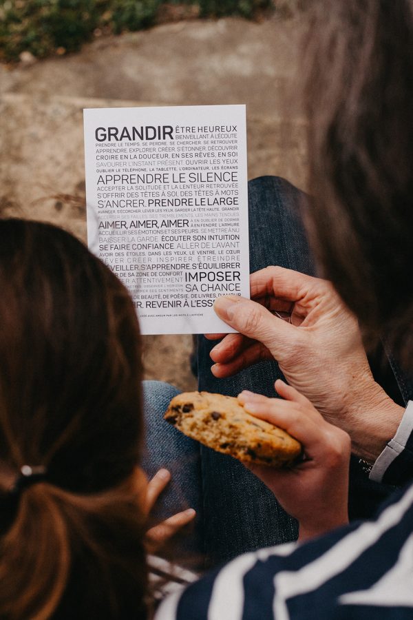 Une femme tient un morceau de papier sur lequel est écrit le mot « Grandir » en guise de cadeau.