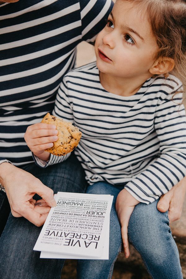 Une petite fille mange un cookie pendant que sa mère lui lit une lettre de Créer.