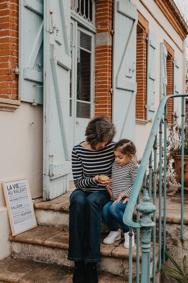 Une mère et sa fille partageant une Slow life - La vie au ralenti, assises sur les marches d'une maison.