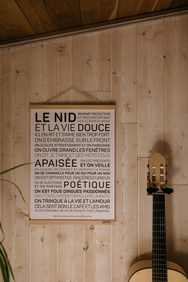 Une affiche avec les mots Maison accrochée au mur à côté d'une guitare acoustique.
