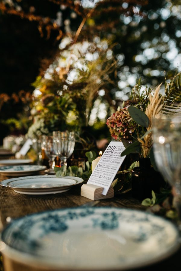 Une table dressée avec des assiettes et des fleurs dessus.