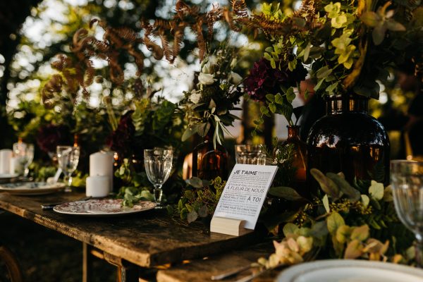 Une table de mariage en plein air dressée avec des fleurs et de la verdure.
