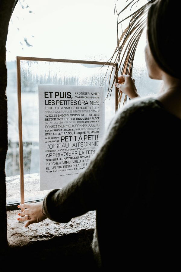 Une femme regarde par la fenêtre une pancarte Écologie & Zéro déchet.