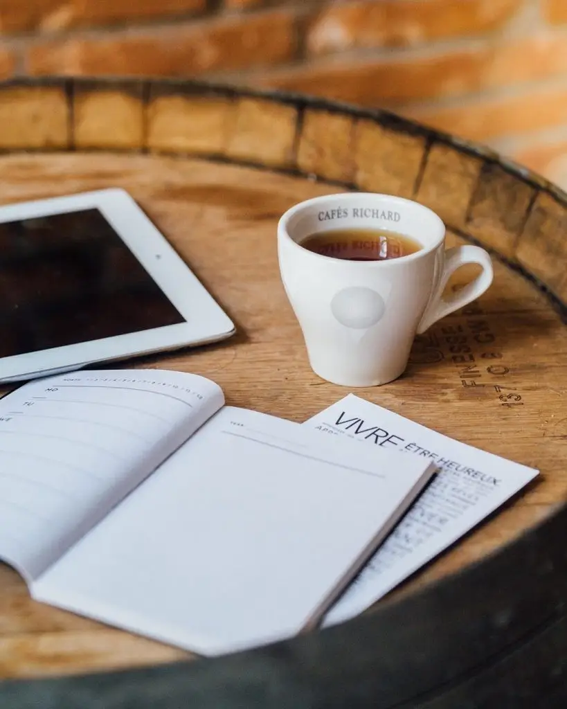 Un iPad sur une table en bois à côté d'une tasse de café.