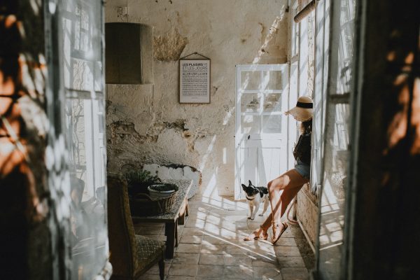 Une femme assise dans une pièce avec Les plaisirs et les jours et un chien regardant par la fenêtre.