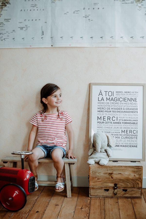 Une petite fille est assise sur un banc en bois devant une carte tenant une Magicienne.