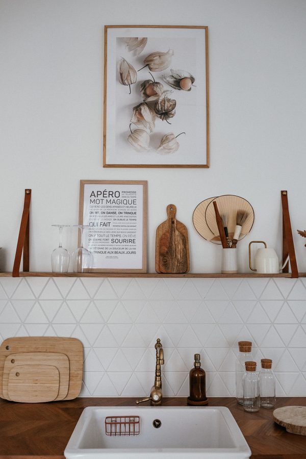 Une cuisine blanche avec un évier en bois, des ustensiles en bois et un Apéro sur le comptoir.