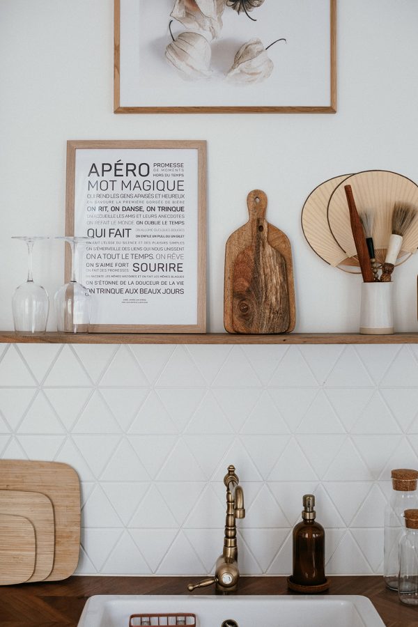 Une cuisine blanche avec des étagères en bois et un Apéro sur l'évier en bois.