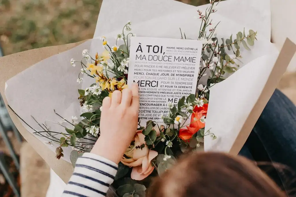 Une fille tient un bouquet de fleurs et lit un livre.