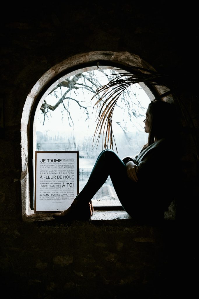 Une femme assise à une fenêtre.