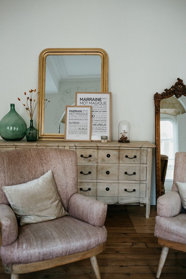 Deux chaises roses, un Parrain et un miroir dans une pièce.