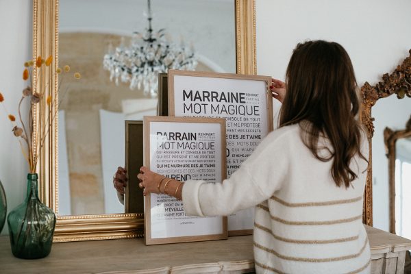 Une femme tient une affiche de Parrain devant un miroir.