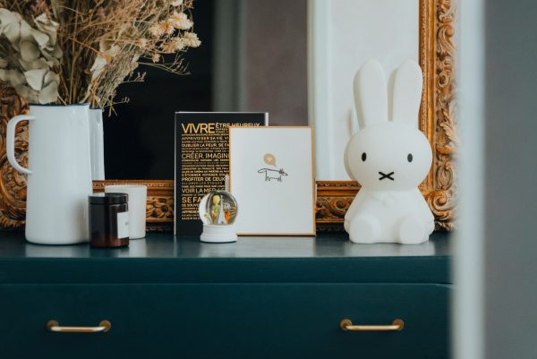 Une commode verte avec un vase, une figurine de lapin et une presse Lettre : Vivre.