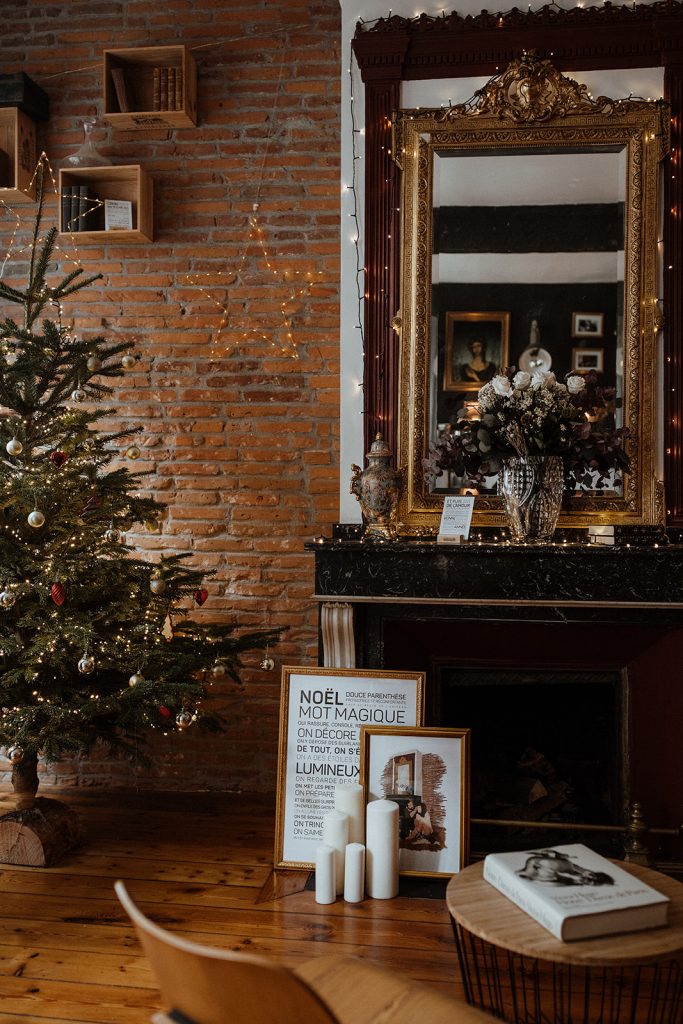 Un salon avec un sapin de Noël orné de cadeaux et une cheminée.