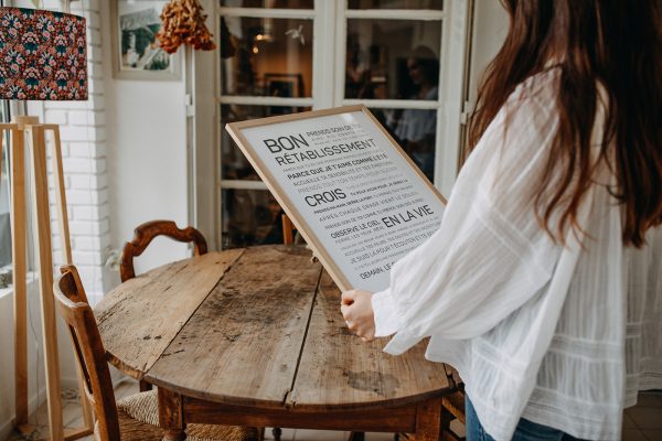 Une femme tenant un cadeau et un menu devant une table en bois.