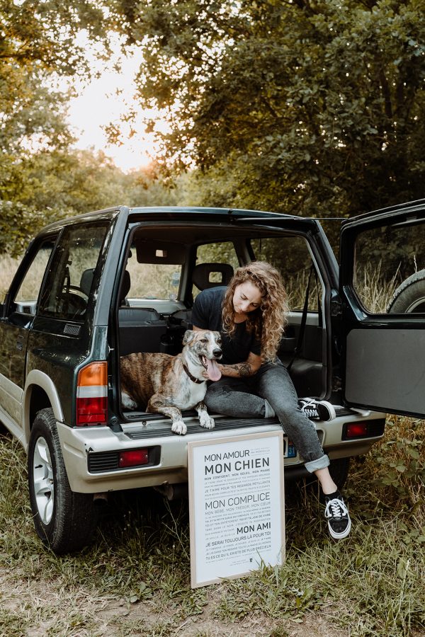 Une femme est assise dans le coffre d'un SUV avec son chien et un autre chien.