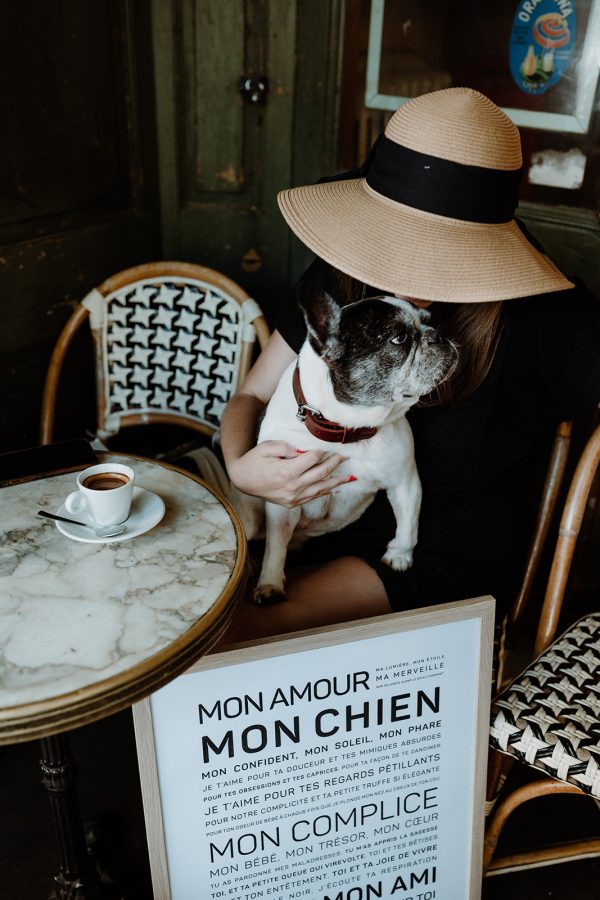 Une femme avec un chapeau et un chien assis à une table avec un Chien.