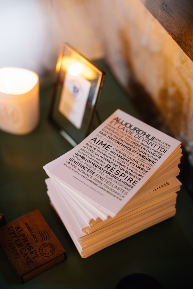 Une idée de cadeau : une pile d'invitations de mariage sur une table à côté d'une bougie.