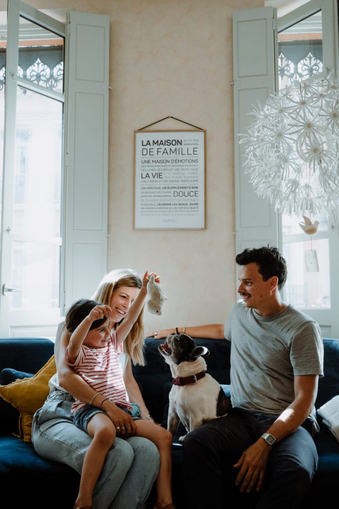 Une famille assise sur un canapé avec un chien, explorant ensemble des idées de cadeaux.