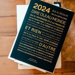 Une presse typographique : 2024 avec les mots "dire oui au monde" posés sur une table, présentant une idée poétique.
