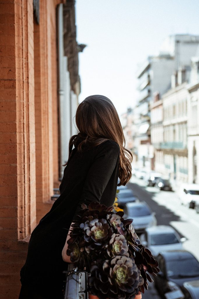 Une jeune femme penchée sur un balcon à Toulouse