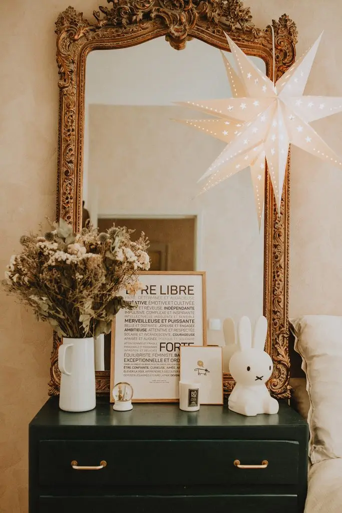 Une chambre avec une commode verte, des mots affiche et un miroir.