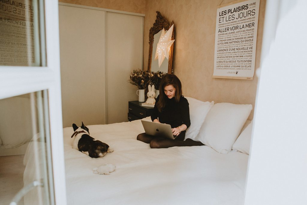 Une femme assise sur un lit avec un chien sur ses genoux, affiche de mots affichée en arrière-plan.