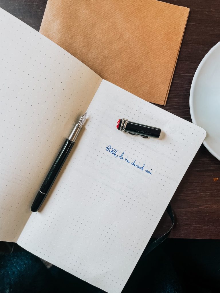 Un cahier avec un stylo plume Montblanc et une tasse de café.
