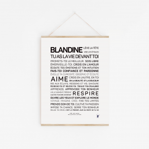 Une affiche en noir et blanc avec un texte français de motivation, encourageant la lectrice nommée Blandine à vivre pleinement, à aimer et à embrasser la vie. L'affiche "Blandine, la vie devant toi" est accrochée sur un mur blanc.
