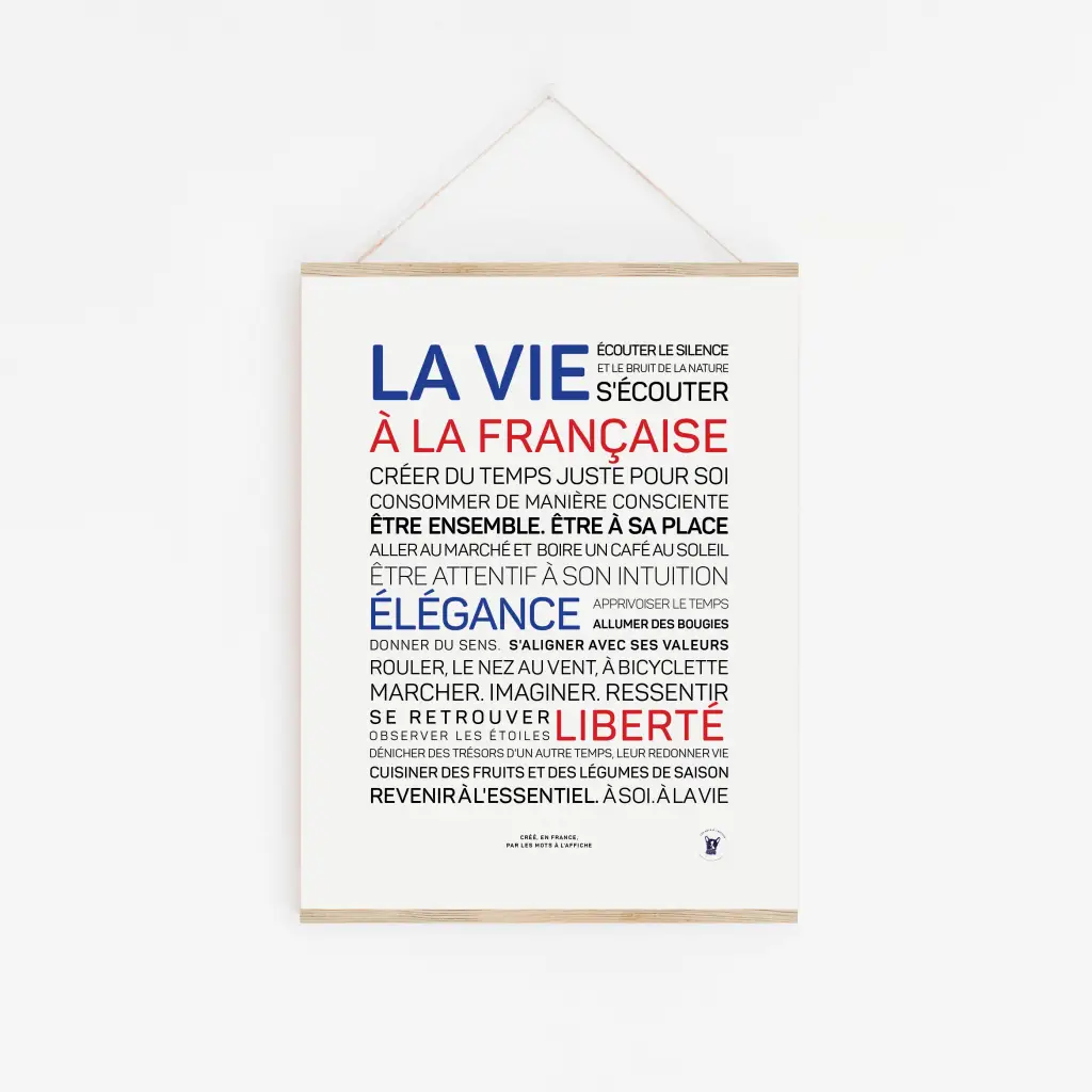 L'affiche « La vie à la française (couleurs) » présente des phrases sur le style de vie français en bleu, rouge et noir. Encadrée de bois et munie d'une ficelle pour une suspension facile, elle constitue un cadeau idéal sur un fond blanc épuré.