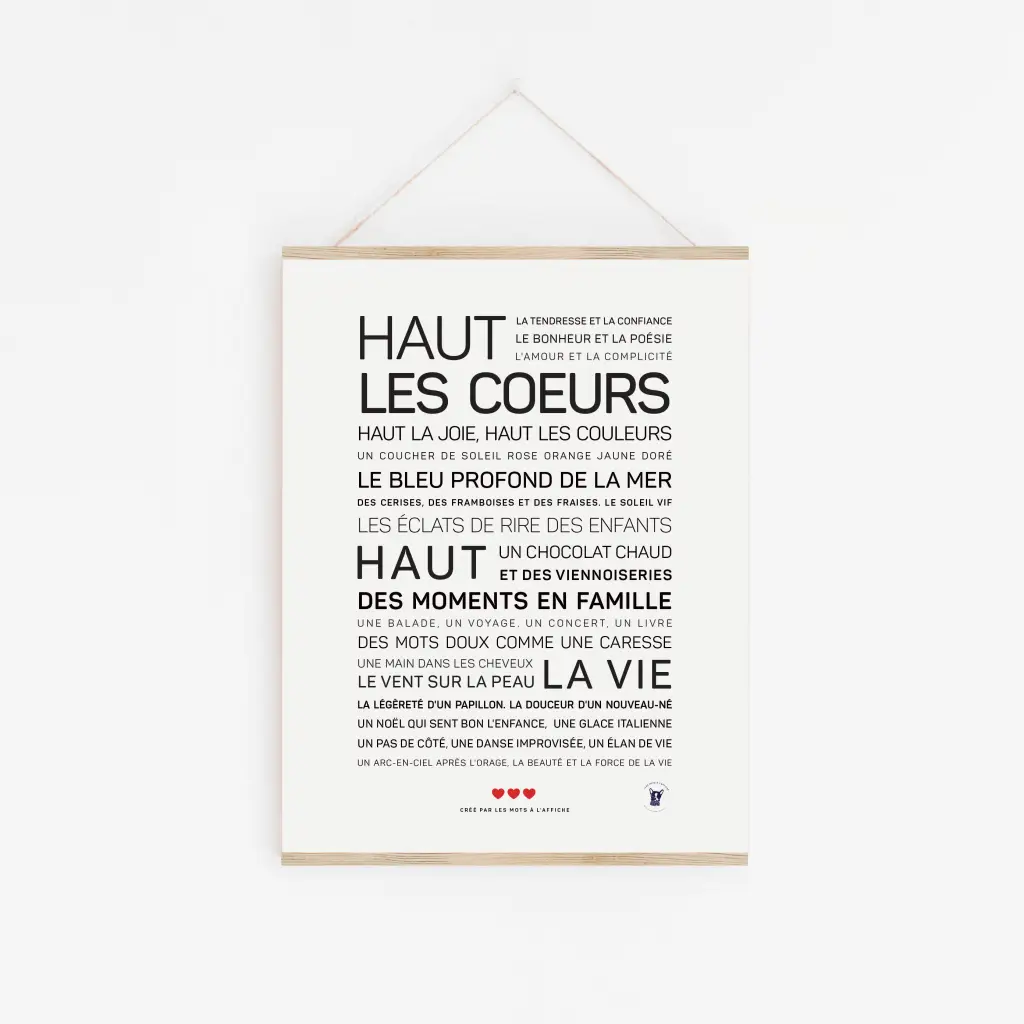 Une affiche encadrée « Haut les cœurs » est accrochée sur un mur blanc, avec un texte inspirant en français sur le bonheur et la famille - une idée cadeau parfaite pour ceux qui chérissent la beauté de la vie.