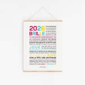 Une affiche encadrée "2025, brille !" comporte un texte inspirant en français, vibrant et noir, centré sur un fond blanc, présenté dans un cintre en bois.
