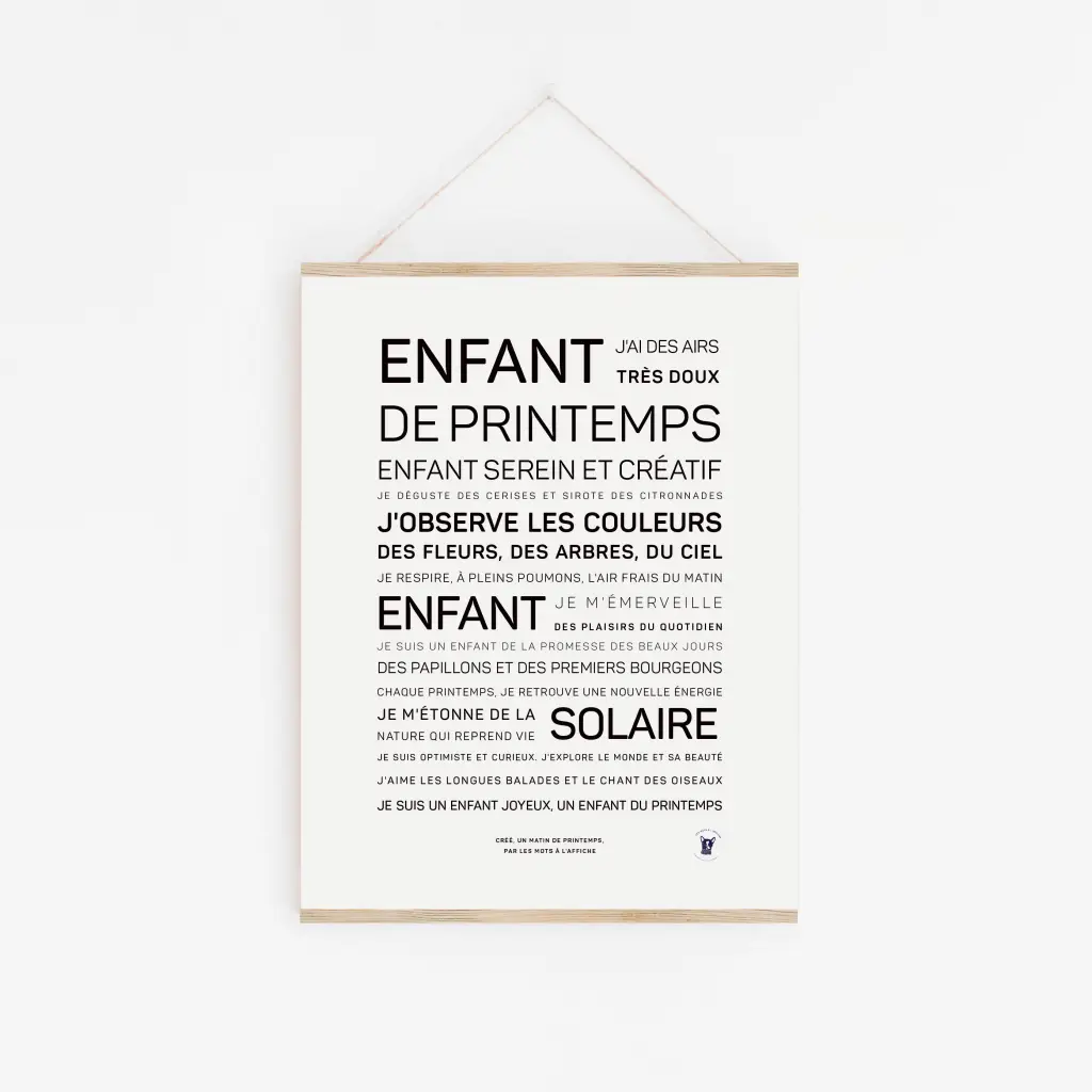 Une affiche blanche « Enfant de printemps » avec du texte français noir dans différentes tailles de police, centrée sur un mur et accrochée par une ficelle à un cintre en bois — une idée cadeau élégante pour tout amateur de décoration.