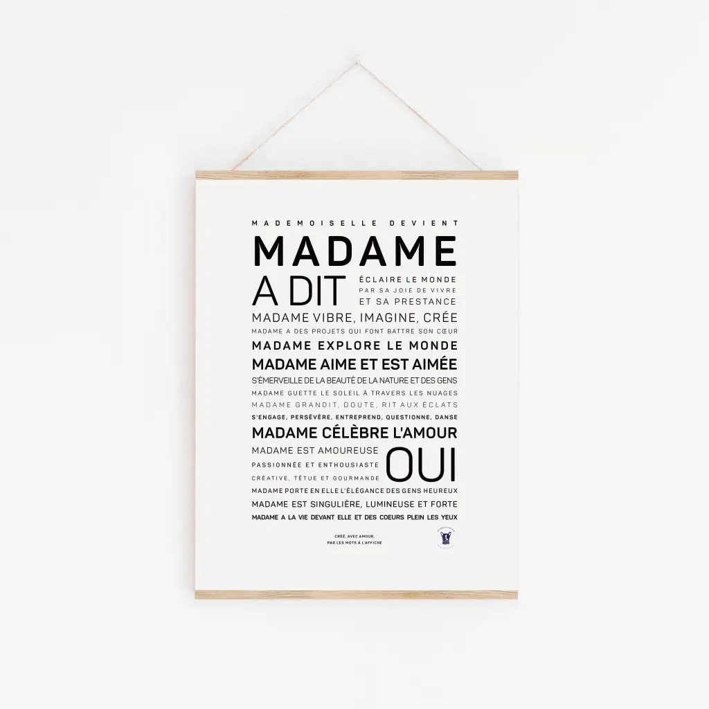 Une affiche minimaliste « Madame a dit oui » avec un texte français noir en gras, centrée sur un fond blanc et suspendue par une fine ficelle - une idée cadeau élégante.