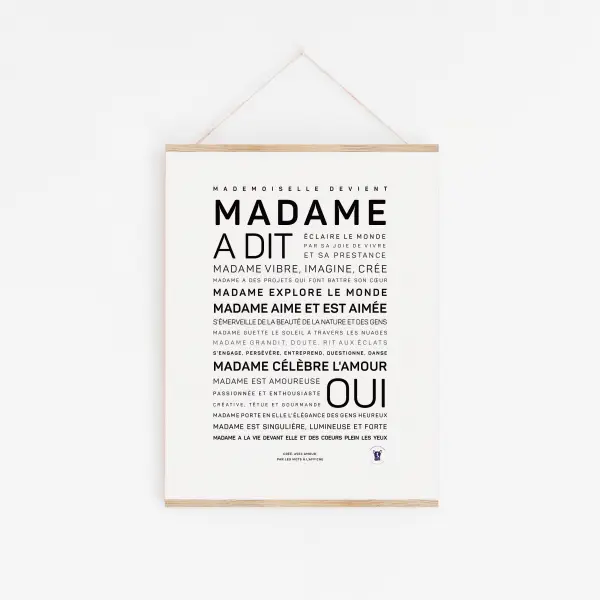 Une affiche minimaliste « Madame a dit oui » avec un texte français noir en gras, centrée sur un fond blanc et suspendue par une fine ficelle - une idée cadeau élégante.
