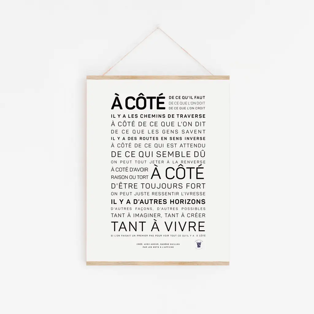 A côté - Nadège Guillou : Affiche avec "À CÔTÉ" en gras, message poétique sur le vivre autrement, noir sur blanc, accrochée par une ficelle - une idée cadeau originale.