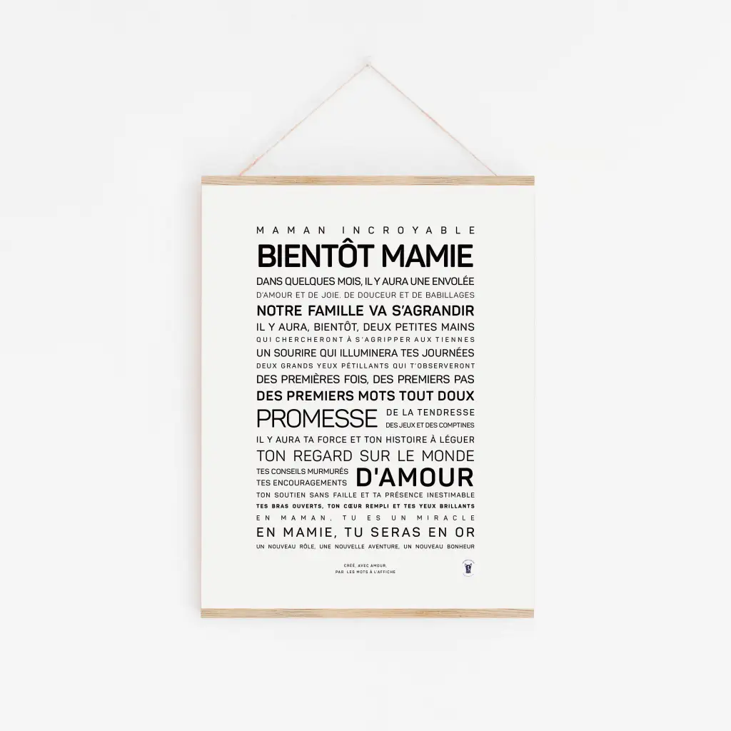 Une affiche avec le texte français « Bientôt mamie » accrochée sur un mur blanc, annonçant l'arrivée prochaine d'un petit-enfant — une charmante idée cadeau, avec des polices audacieuses et régulières mettant en valeur le message.