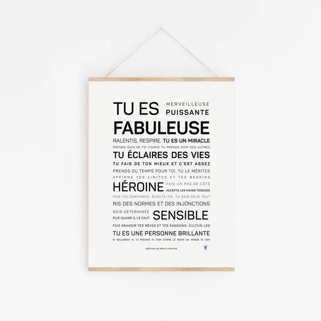 Affiche minimaliste "Tu es fabuleuse" en français : texte motivant noir centré sur fond blanc, suspendu par une ficelle au mur clair—parfaite idée cadeau pour inspirer vos proches.