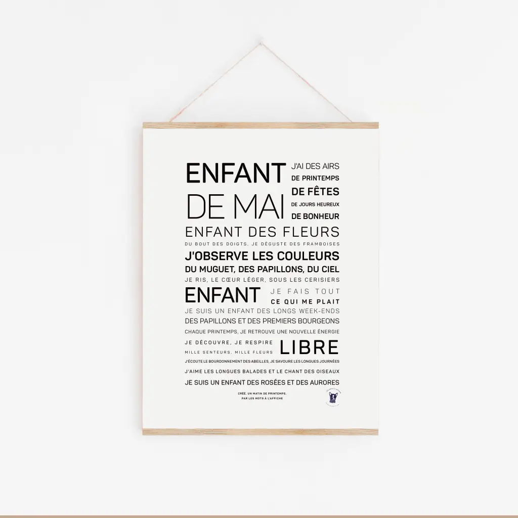 L'affiche blanche « Enfant de mai » présente des phrases poétiques en français dans différentes tailles et poids de police, élégamment présentées dans un cadre en bois clair sur un mur blanc - un cadeau idéal pour toute occasion.