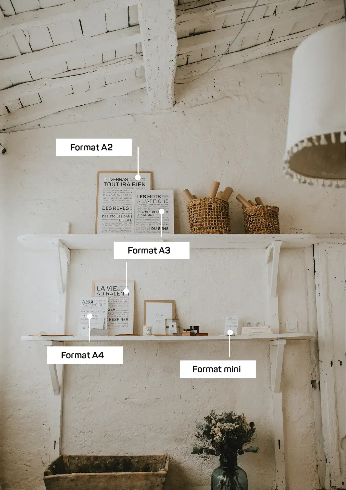 Deux étagères murales blanches présentent des impressions encadrées aux formats A2, A3, A4 et mini - une idée cadeau inspirante - aux côtés de paniers, de livres et d'un vase de fleurs dans un décor intérieur rustique.