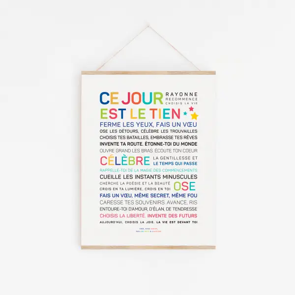 Une impression d'art encadrée intitulée "Ce jour est le tien !" présente des phrases de motivation multicolores en français sur le fait de vivre dans le présent et d'apprécier chaque moment, affichées sur un mur blanc.