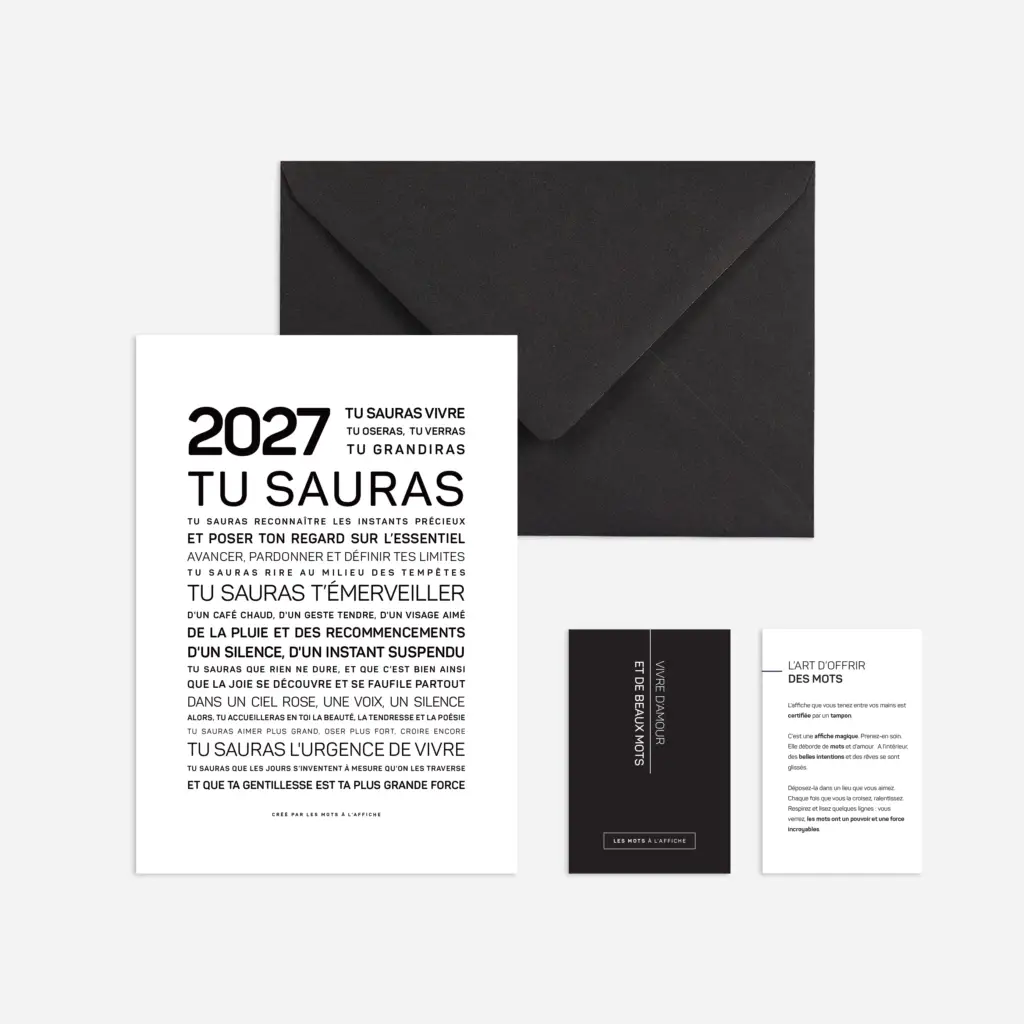 Une carte sur laquelle figure en gros caractères le texte en français « 2026, tu sauras », ainsi qu'un autre texte, posée à côté d'une enveloppe noire et de deux cartes plus petites, le tout sur un fond clair.