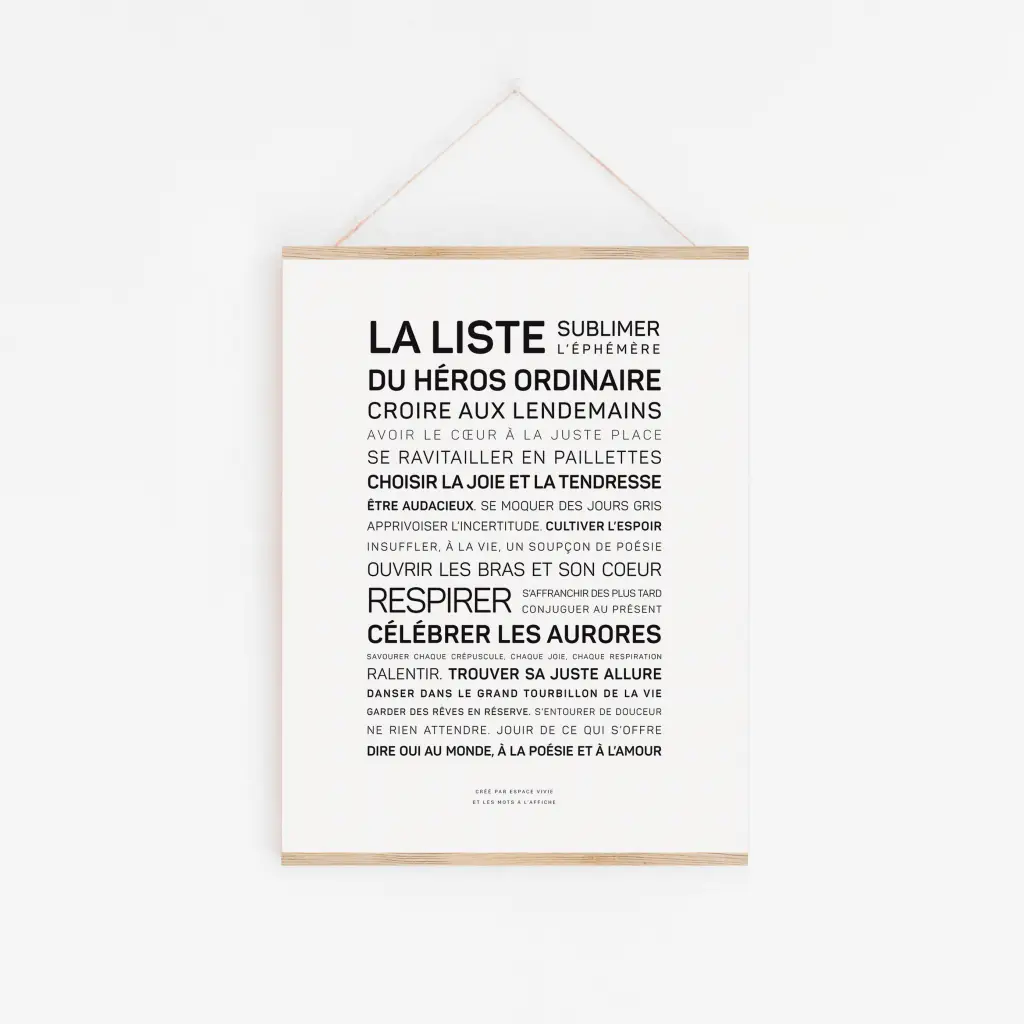 La liste du héros ordinaire" est une affiche blanche avec un texte en français dans différentes tailles de police, qui contient des phrases inspirantes sur les héros ordinaires, la gentillesse, la tendresse et l'amour. Elle est accrochée au mur par une fine ficelle.
