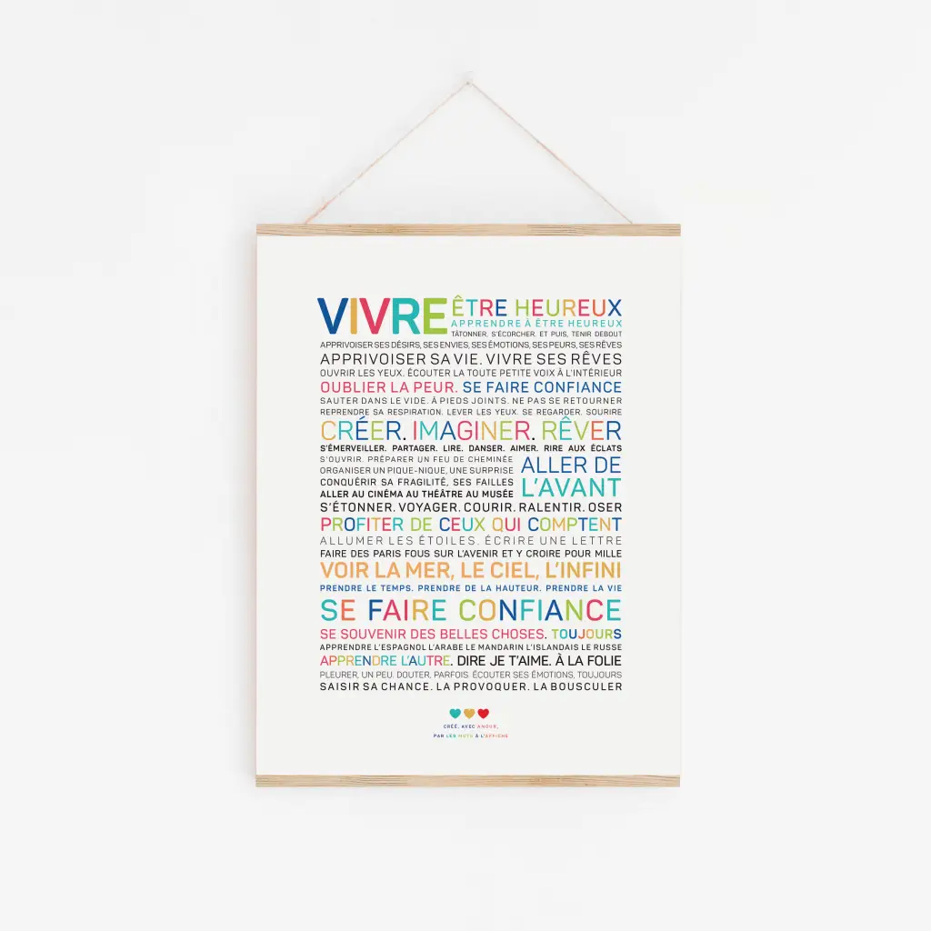 L'affiche "Vivre" est un design minimaliste avec des mots français colorés sur fond blanc, encadrés dans du bois clair et suspendus par une ficelle.