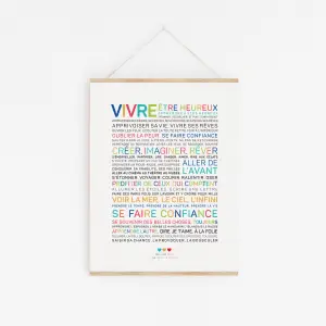 L'affiche "Vivre" est un design minimaliste avec des mots français colorés sur fond blanc, encadrés dans du bois clair et suspendus par une ficelle.