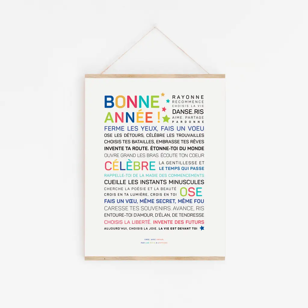 Une impression encadrée du Nouvel An français "2026, ose te choisir" avec un texte de motivation coloré et gras est suspendue à un mur blanc par une fine ficelle.