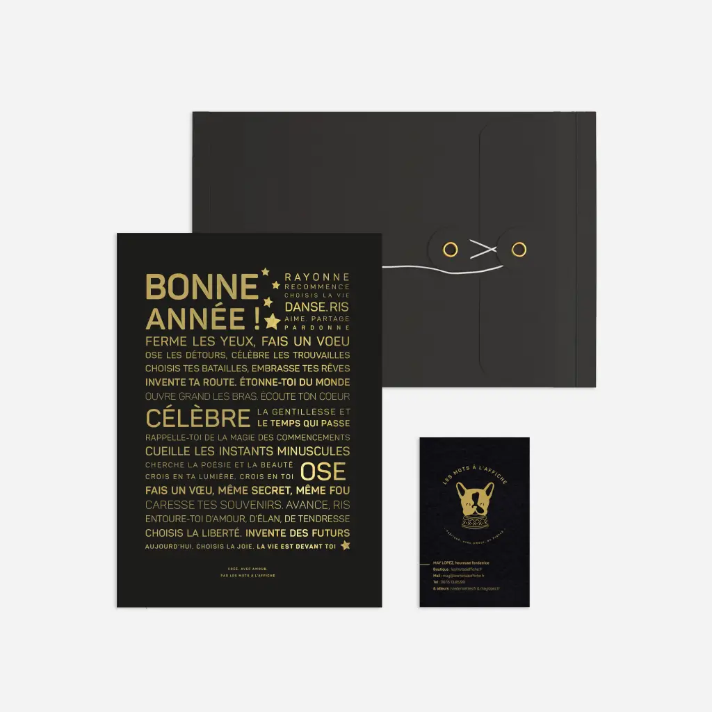 Le set Letter press : Bonne année comprend une chemise noire avec fermeture par cordon, une carte de texte en français noir et or, ainsi qu'une petite carte illustrée d'un chat doré, le tout sur fond blanc.