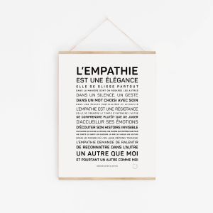 Une affiche encadrée intitulée "L'empathie est une élégance" est accrochée à un mur blanc, affichant un texte en français sur l'empathie en différentes tailles de caractères.