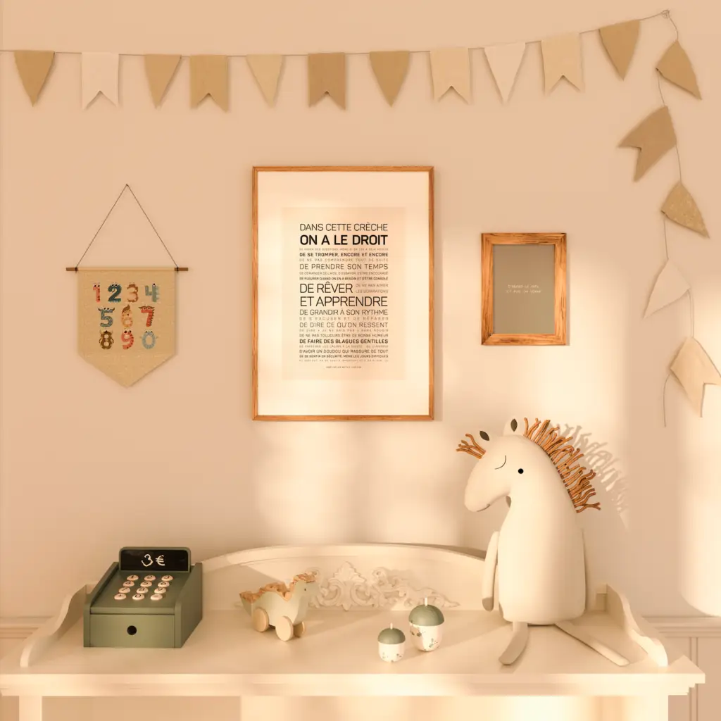 Le mur de la crèche est décoré d'une affiche « Dans cette crèche, on a le droit », de banderoles avec des chiffres et d'une table blanche sur laquelle sont disposés une caisse enregistreuse jouet, un cheval en peluche, une petite voiture et des figurines en forme de champignons.