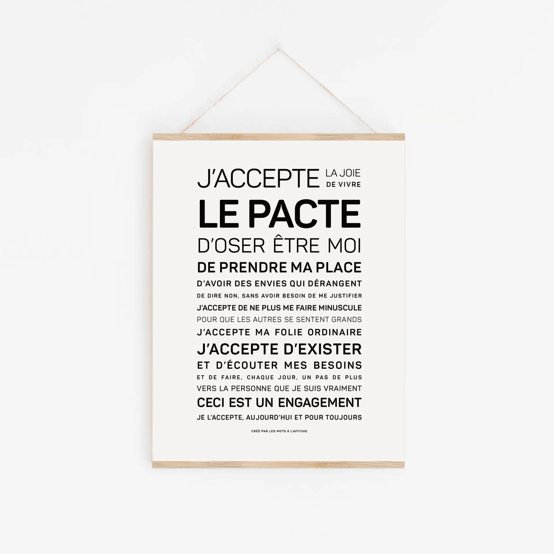 Une affiche blanche intitulée « Dans cette école, on a le droit (Copie) », comportant un texte en français écrit en noir sur le thème de l'acceptation de soi, est accrochée à un cadre en bois sur un mur blanc.